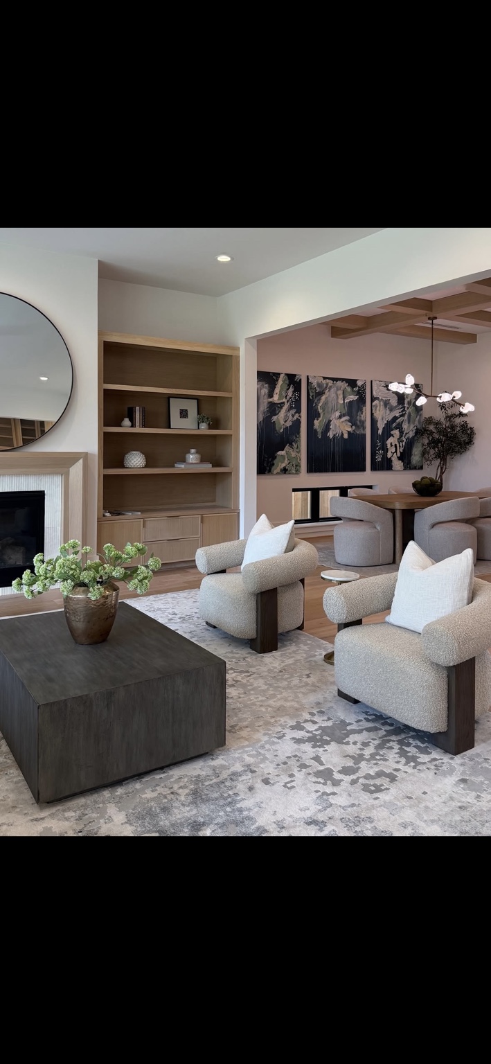 Living room with sculptural upholstered chairs, a dark wood coffee table, and custom shelving