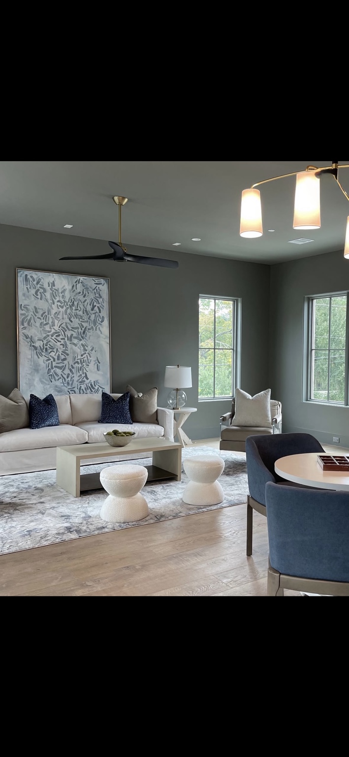 Living space with a cream sofa, navy accents, sculptural stools, and large artwork